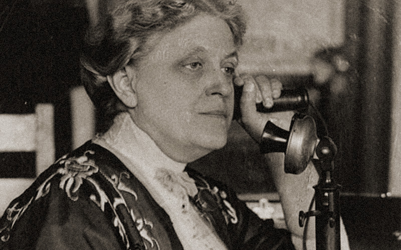 Photo of Carrie Chapman Catt speaking on an old fashioned candlestick phone. LOC Carrie Chapman Catt. Collections of the Library of Congress.